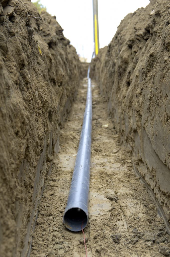 pvc pipe used for underground wire runs sitting at the bottom of a dirt trench