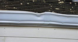 The angle of impact, when hailstones strike asphalt shingles, will leave a fracture or pock mark where the granules have been removed and the underlying asphalt layer is left exposed as shown at right. This can cause damage severe enough to warrant a roof replacement. Other signs of hail damage occur on gutters, as shown by the dents and distortion in the photo at left.