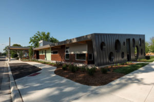 The metal roof extends out in eaves at the sides of the facility. The swiss cheese pattern is evident on one end of the facility.