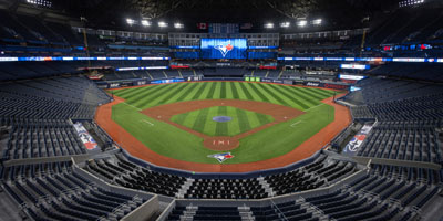 An empty Rogers Centre poised for play, showcasing its expansive seating and state-of-the-art field under dramatic lighting.