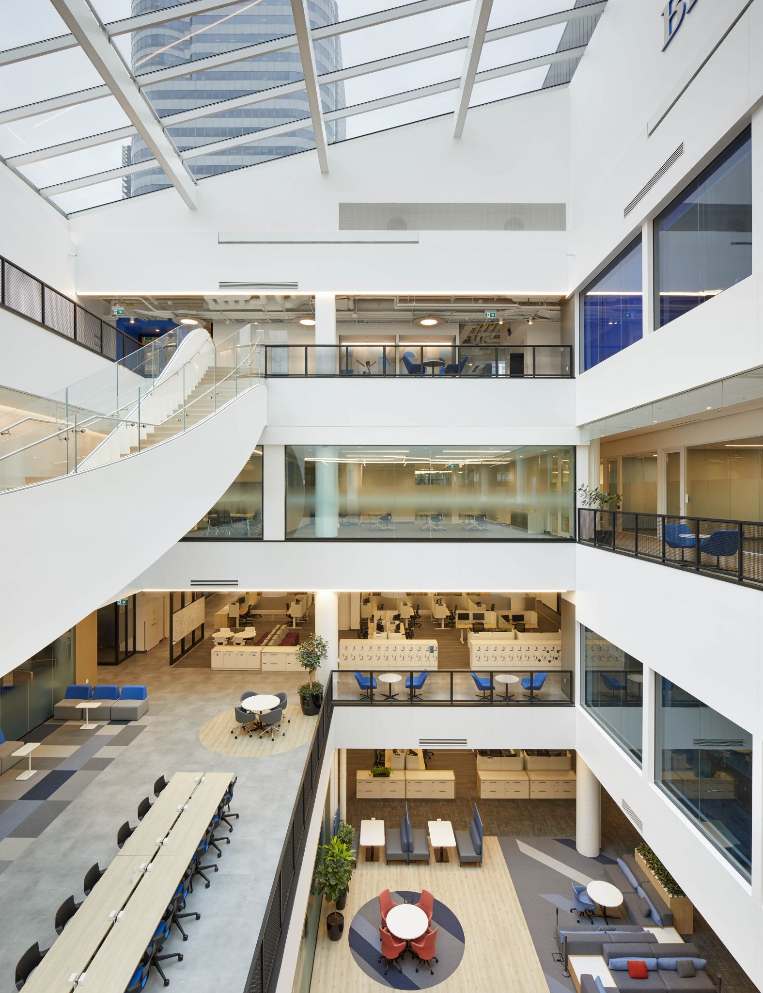 A modern office interior, featuring open spaces, glass walls, and a skylight, with collaborative areas and workstations.