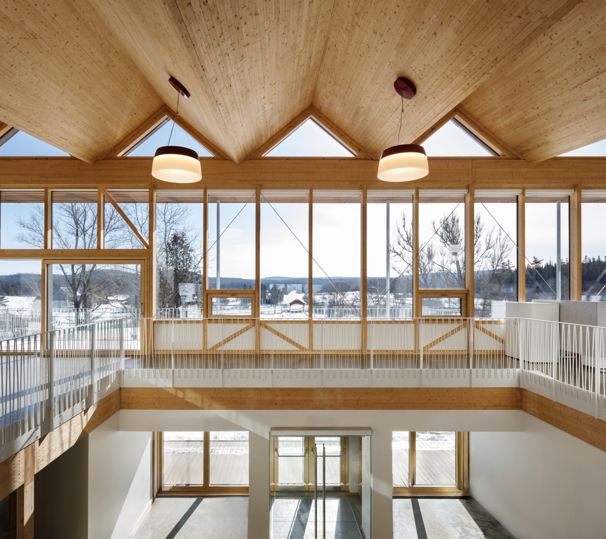 Modern interior of a public building featuring exposed timber framing, high vaulted ceilings, and large glass windows.