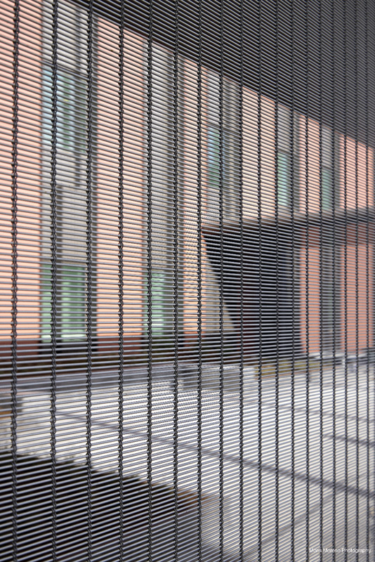 A close-up of a textured black screen reveals blurred architectural elements in the background, showcasing modern building design.