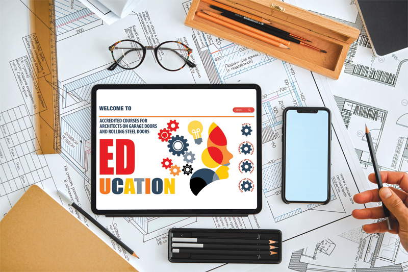 A tablet displaying an educational course website on garage doors, surrounded by architectural plans, a phone, glasses, and stationery.