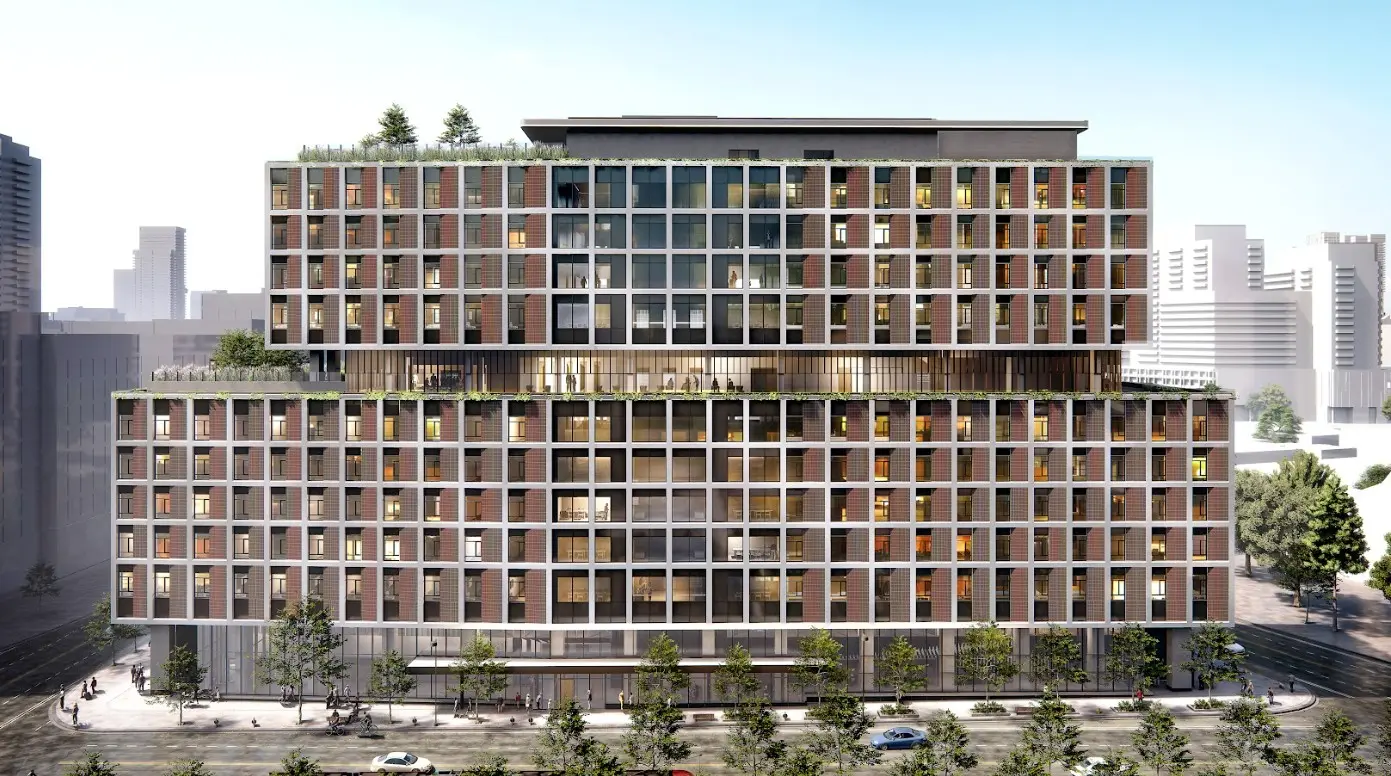 A modern multi-story building featuring green roofs, large glass windows, and a mix of brick and contemporary design elements.