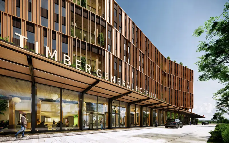 A modern multi-story building with wood-paneled exterior, featuring greenery on rooftops, an emergency entrance, and surrounding landscaping.