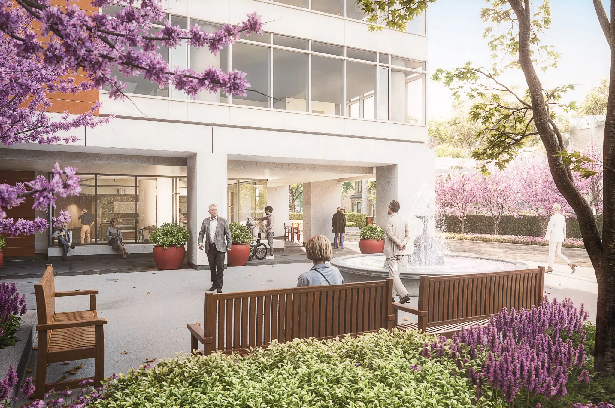 Outdoor courtyard with benches, a fountain, and people walking and sitting among blooming trees and plants near a modern building.