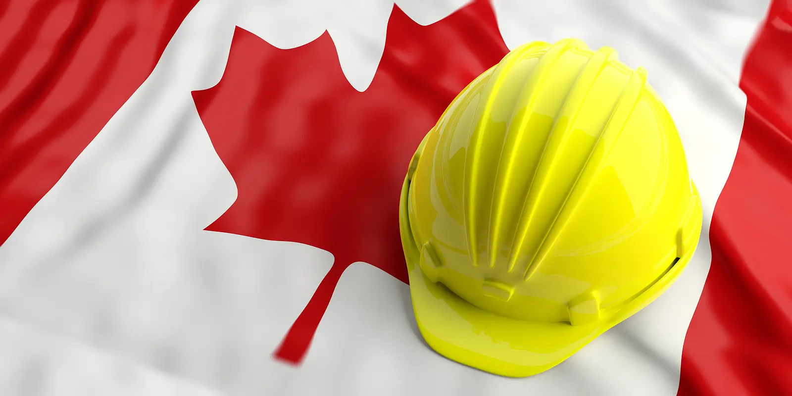 A bright yellow hard hat rests on a Canadian flag. The flag's red maple leaf and white background highlight themes of industry and national pride.