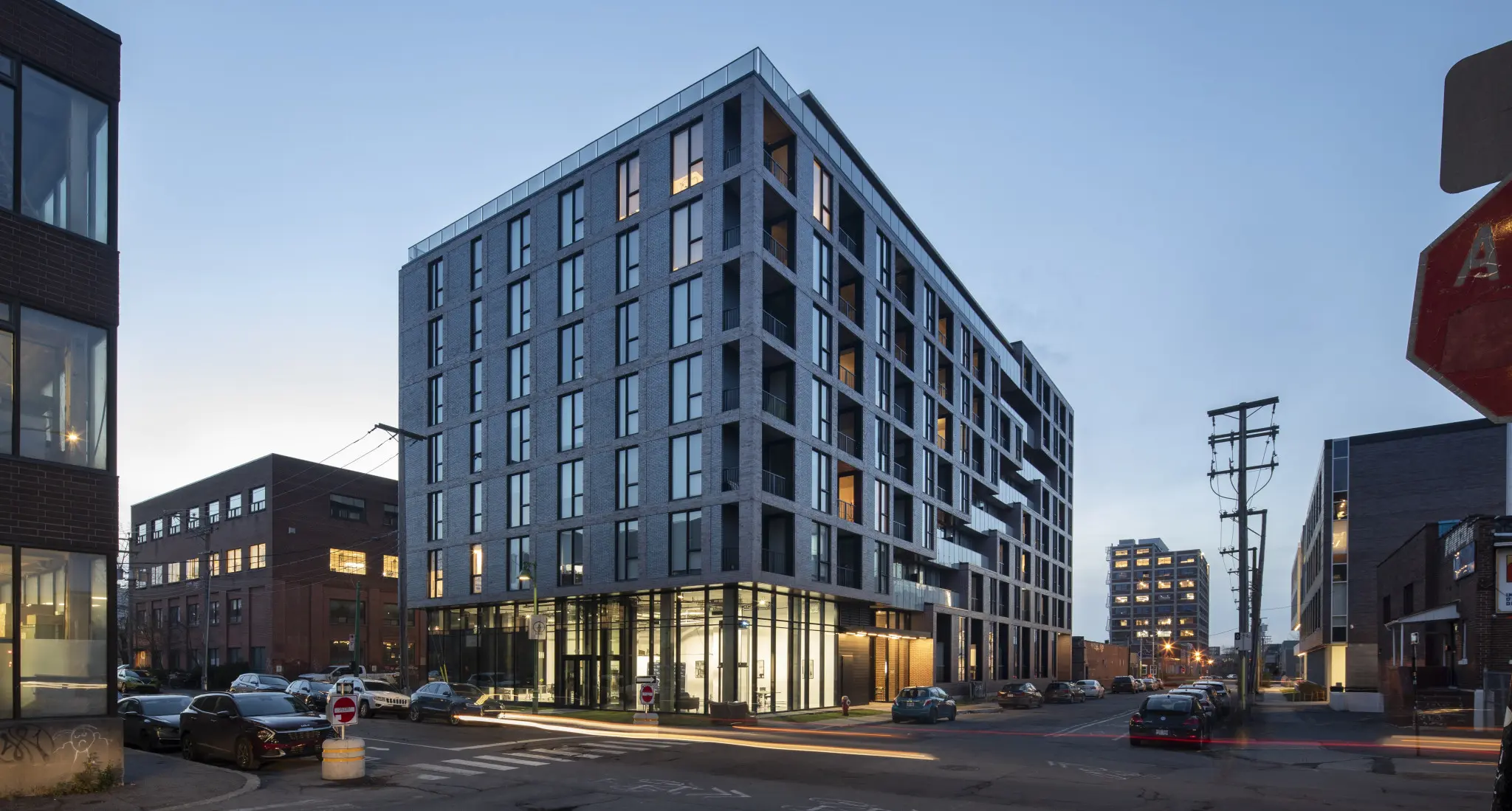 Modern urban building at dusk, with large glass windows and a sleek design. Streetlights illuminate the scene, creating a calm, urban atmosphere.