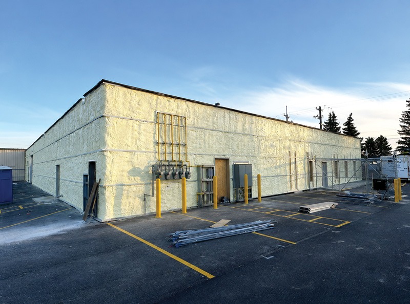 A large building with yellow walls, surrounded by a spacious parking lot.