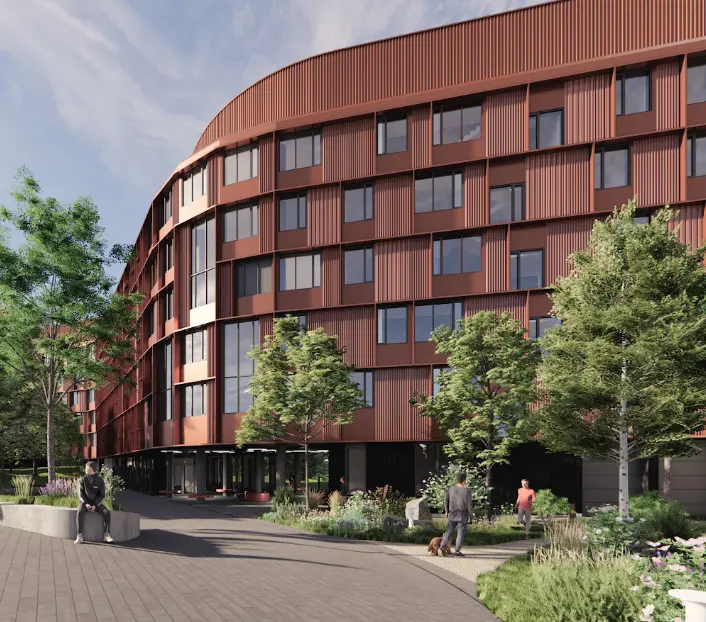 A modern, curved building with red panels and large windows stands amidst lush greenery and landscaped paths. People are walking and sitting, creating a relaxed atmosphere.