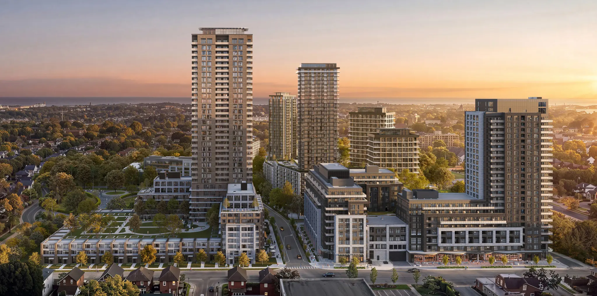 A modern urban landscape with multiple high-rise buildings, featuring a sunset backdrop that casts warm colors across the sky and highlighting green landscaped areas among the structures.