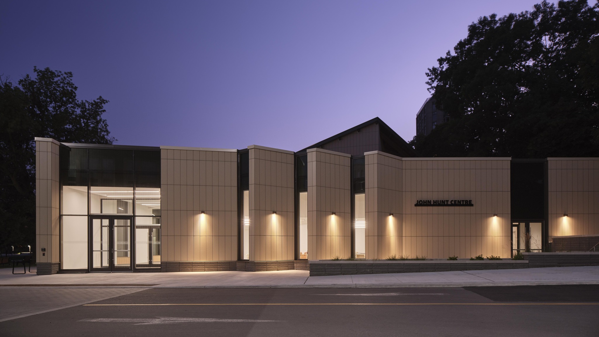 Modern illuminated building at dusk with the sign “JOHN HUNT CENTRE” on its façade.